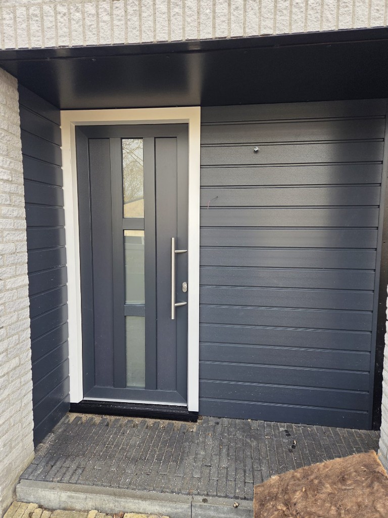Antraciete voordeur met melkglas in portiek